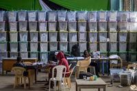 Electoral workers sit next to stacked ballot boxes after tallying finished in the Shauri Moyo area of Nairobi, Kenya Friday, Aug. 12, 2022. Kenyans are waiting for the results of a close presidential election in which the turnout was lower than usual. (AP Photo/Ben Curtis)