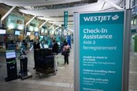 WestJet Airlines says a system outage Thursday morning is delaying some flights and intermittently impacting the company's operations. A Westjet employee assists people checking in for a domestic flight at Vancouver International Airport, in Richmond, B.C., on Thursday, January 21, 2021. THE CANADIAN PRESS/Darryl Dyck