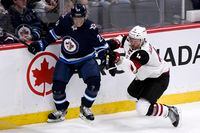 The Winnipeg Jets' Cody Eakin is checked by the Arizona Coyotes' Niklas Hjalmarsson during first-period NHL action in Winnipeg on Monday.