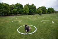 A visitor sits in one of the freshly painted circles at Trinity Bellwoods Park on May 28 2020. After the park was crowded with people last weekend, not adhering to physical distancing guidelines, the eight foot circles, spaced eight feet from other circles, were painted to help people keep their distance.. Around 300-400 circles can be painted in the park if necessary.