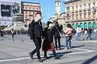 A couple wearing a protective facemask walk across the Piazza del Duomo, in central Milan, on February 24, 2020 as security measures were taken in northern Italy against the COVID-19 the novel coronavirus. - Italy reported on February 24, 2020 its fourth death from the new coronavirus, an 84-year old man in the northern Lombardy region, as the number of people contracting the virus continued to mount. (Photo by Andreas SOLARO / AFP) (Photo by ANDREAS SOLARO/AFP via Getty Images)