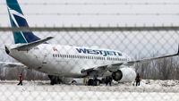 Workers shovel snow, Monday February 18, 2008 under a Westjet passenger jet that slid off the end of a runway at Ottawa International Airport, late Sunday. No injuries were reported on the flight from Calgary. THE CANADIAN PRESS/Fred Chartrand