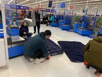 Customers stranded at a Walmart in Chatham, Ont., inflate air mattresses in the check out area of the store. Nearly 100 customers and staff hunkered down at the store after police shut roads in town due to a snowstorm.
