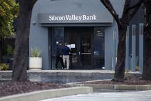 A man puts a sign on the door of the Silicon Valley Bank as an onlooker watches at the bank’s headquarters in Santa Clara, California, U.S. March 10, 2023. REUTERS/Nathan Frandino/File Photo