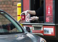 A Tim Hortons employee hands out coffee from a drive-through window to a customer in Mississauga, Ont., on Tuesday, March 17, 2020. THE CANADIAN PRESS/Nathan Denette