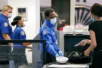 TSA officers wear protective masks at a security screening area at Seattle-Tacoma International Airport Monday, May 18, 2020, in SeaTac, Wash. Airlines say they are stepping up security on flights to Washington before next weeks inauguration of President-elect Joe Biden. Delta, United and Alaska airlines said Thursday, Jan. 14, 2021 they will bar passengers flying to Washington from putting guns in checked bags. (AP Photo/Elaine Thompson)