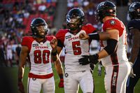 Ottawa Redblacks quarterback Caleb Evans (5) celebrates with teammates wide receiver Nate Behar (80) and offensive lineman Connor Berglof (59) after Evans ran the ball forward during fourth quarter CFL action against, in Toronto on Sunday July, 31, 2022. THE CANADIAN PRESS/Christopher Katsarov