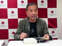 Japanese novelist Haruki Murakami signs his autograph on his novel "Killing Commendatore" during a press conference at Waseda University in Tokyo Saturday, Nov. 3, 2018. (AP Photo/Eugene Hoshiko)