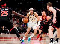 Indiana Pacers guard Andrew Nembhard (2) drives between Toronto Raptors forward Chris Boucher (25), guard Malachi Flynn (22) and centre Jakob Poeltl (19) during second half NBA basketball action in Toronto on Wednesday, March 22, 2023. THE CANADIAN PRESS/Frank Gunn