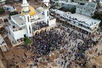 People gather for a demonstration outside the surviving Al-Sahaba mosque in Libya's eastern city of Derna on September 18, 2023, as they protest against government neglect to the two dams which broke and led to the deadly flash floods that hit the city the prior week. A week after a tsunami-sized flash flood devastated the Libyan coastal city of Derna, sweeping thousands to their deaths, the international aid effort to help the grieving survivors slowly gathered pace. The enormous flood, fuelled by torrential rains on September 10, had broken through two upstream dams and sent a giant wave crashing down the previously dry river bed, or wadi, that bisects the city of about 100,000 people. (Photo by Hussam AHMED / AFP) (Photo by HUSSAM AHMED/AFP via Getty Images)