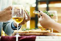 Couple in an italian restaurant eating pizza and drinking wine. Selective focus on pizza slices.