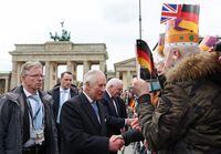 Britain's King Charles III and German President Frank-Walter Steinmeier (C) shake hands with members of the public after a ceremonial welcome at Brandenburg Gate in Berlin, on March 29, 2023. - Britain's King Charles III began his first state visit, having postponed a trip to France due to widespread political protests. Charles will undertake engagements in the German capital and in Brandenburg before heading to Hamburg during the three-day tour. (Photo by Adrian DENNIS / POOL / AFP) (Photo by ADRIAN DENNIS/POOL/AFP via Getty Images)