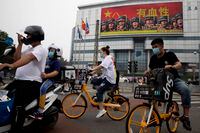 Residents ride past Chinese military propaganda with the slogan 'Heroic', in Beijing, on Aug. 26, 2020.