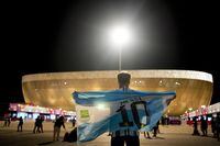 A man holds an Argentinian flag prior to the World Cup quarterfinal soccer match between the Netherlands and Argentina, outside the Lusail Stadium in Lusail, Qatar, Friday, Dec. 9, 2022. (AP Photo/Natacha Pisarenko)
