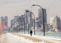 A person jogs next to a backdrop of the Montreal skyline as ice fog rises off the St. Lawrence River in Montreal, Saturday, Jan. 22, 2022. An extreme cold weather warning is in effect for Montreal, with temperatures forecast to dip to -27 C by Friday night, increasing the risk of frostbite and hypothermia, especially for the city's vulnerable homeless population. THE CANADIAN PRESS/Graham Hughes