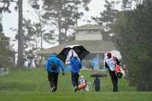 Kurt Kitayama, center, walks back up the 10th fairway of the Spyglass Hill Golf Course after the third round of the AT&T Pebble Beach Pro-Am golf tournament was suspended because of inclement weather in Pebble Beach, Calif., Saturday, Feb. 4, 2023. (AP Photo/Eric Risberg)