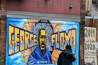A man walks past the mural of George Floyd near the makeshift memorial of George Floyd before the third day of jury selection begins in the trial of former Minneapolis Police officer Derek Chauvin who is accused of killing Floyd, in Minneapolis, Minnesota on March 10, 2021. - The first jurors were selected on March 9, 2021 in the high-profile trial of the white police officer accused of killing George Floyd, an African-American man whose death laid bare racial wounds in the United States and sparked "Black Lives Matter" protests across the globe. Former Minneapolis Police Department officer Derek Chauvin is facing charges of second-degree murder and manslaughter in connection with Floyd's May 25 death, which was captured by bystanders on smartphone video. (Photo by CHANDAN KHANNA / AFP) (Photo by CHANDAN KHANNA/AFP via Getty Images)