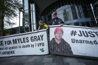 Protesters hold banners with a photograph of Myles Gray, who died following a confrontation with several police officers in 2015, before the start of a coroner's inquest into his death, in Burnaby, B.C., on Monday, April 17, 2023. A Vancouver police officer has described efforts to resuscitate Gray at the inquest. THE CANADIAN PRESS/Darryl Dyck