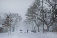 A man pulls a child on a sled across a street through blowing snow during a winter storm in Halifax on Saturday, January 29, 2022. THE CANADIAN PRESS/Kelly Clark