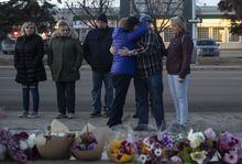 The families of constables Brett Ryan and Travis Jordan look over flowers laid at a vigil for Ryan and Jordan, in Edmonton on March 17, 2023. The families of two Edmonton police officers who were fatally shot earlier this month have issued statements thanking the public for their support. THE CANADIAN PRESS/Jason Franson