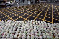 A man wearing protective clothing as a preventive measure against the COVID-19 coronavirus walks past bags of vegetables being prepared for delivery on an almost empty street in Wuhan, in China's central Hubei province on February 26, 2020. - China on February 26 reported 52 new coronavirus deaths, the lowest figure in more than three weeks, bringing the death toll to 2,715. All the new deaths were in the outbreak epicentre Hubei province, which accounted for 401 of the 406 new infections reported on February 26, the National Health Commission said. (Photo by STR / AFP) / China OUT (Photo by STR/AFP via Getty Images)