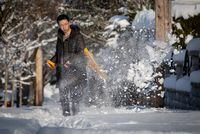 A man shovels snow from the sidewalk in front of a house after 21 centimetres of snow fell overnight, in Vancouver, on Thursday, Dec. 30, 2021. THE CANADIAN PRESS/Darryl Dyck