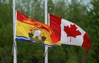 The New Brunswick and Canadian flags fly at half mast outside the Moncton Coliseum in Moncton, N.B. on Monday, June 9, 2014., where a regimental funeral will take place Tuesday for the the three RCMP officers who were slain in Moncton last week. THE CANADIAN PRESS/Sean Kilpatrick
