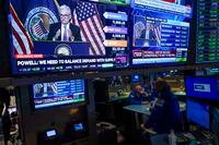 As traders work and watch, a news conference held by Federal Reserve Chair Jerome Powell is displayed at the New York Stock Exchange in New York, Wednesday, July 27.
