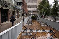 Restaurant tables are turned upside down as a pedestrian walks past the patio in downtown Halifax ahead of Hurricane Fiona making landfall on Sept. 23, 2022.
