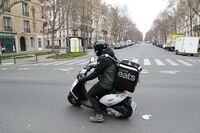 An Uber Eats delivery man rides a moped in Paris on March 22, 2020, as a strict lockdown comes into effect to stop spread of the COVID-19 caused by novel coronavirus in the country prohibiting all but essential outings in a bid to curb coronavirus spread. (Photo by Ludovic MARIN / AFP) (Photo by LUDOVIC MARIN/AFP via Getty Images)