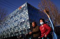 People ride an electric tricycle past the headquarters of the Chinese ride-hailing service Didi in Beijing on Dec. 3.