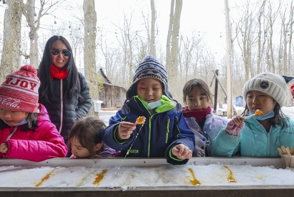 Children roll up and taste maple taffy at Sucrerie de la Montagne, a sugar shack or cabane a sucre, in Rigaud, Quebec, March 23, 2022.   (Christinne Muschi /The Globe and Mail)