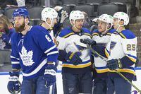St. Louis Blues' Pavel Buchnevich (centre) celebrates with teammates after scoring as Toronto Maple Leafs' Jake Muzzin skates past during first period NHL hockey action in Toronto, on Saturday, February 19, 2022.THE CANADIAN PRESS/Chris Young