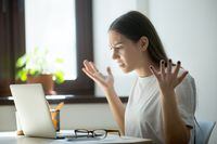 Millennial generation young adult woman looking in laptop computer, fling arms up.  She just found mistake in last assignment, error in contract, disagreement in email or dissatisfied buyer message.