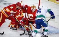 Vancouver Canucks’ Nils Hoglander, right, scrambles for the puck in front of Calgary Flames goalie Jacob Markstrom, centre, and Mark Giordano during first period NHL hockey action in Calgary, Saturday, Jan. 16, 2021.THE CANADIAN PRESS/Jeff McIntosh