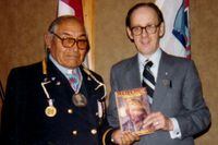 Hugh Dempsey, right, as master of ceremonies at a retirement ceremony for Head Chief Jim Shot Both Sides of the Blood Reserve in 1980. During the occasions, Mr. Dempsey presented the Chief with the book, Red Crow, which chronicles the chief's great grandfather. Courtesy of the Family.