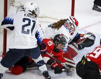 Canada's Melodie Daoust, centre, is checked by Hilary Knight, left, of the United States, into goalie Nicole Hensley during second period gold medal final IIHF Women's World Championship hockey action in Calgary, Tuesday, Aug. 31, 2021.THE CANADIAN PRESS/Jeff McIntosh