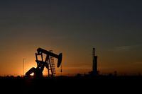 FILE PHOTO: A pump jack operates in front of a drilling rig at sunset in an oil field in Midland, Texas U.S. August 22, 2018.  REUTERS/Nick Oxford/File Photo