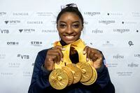In this Oct. 13, 2019, file photo, Simone Biles of the United States shows her five gold medals at the Gymnastics World Championships in Stuttgart, Germany.