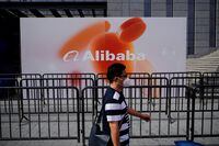 FILE PHOTO: A person walks past a sign of Alibaba Group during the World Artificial Intelligence Conference, following the coronavirus disease (COVID-19) outbreak, in Shanghai, China, September 1, 2022. REUTERS/Aly Song