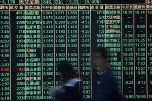FILE PHOTO: People walk past an electronic board showing stock information at a brokerage house in Hangzhou, Zhejiang province, China February 9, 2018. REUTERS/Stringer/File Photo