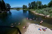 FILE - In this June 30, 2021 file photo Missoulians cool off in the Bitterroot River as temperatures crested 100 degrees Fahrenheit in Missoula, Mont. The Pacific Northwest is bracing for another major, multi-day heat wave in mid-August 2021 just a month after temperatures soared as high as 116 F in a record-shattering heat event that killed scores of the most vulnerable across the region. (AP Photo/Tommy Martino, File)