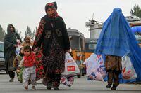 Afghan women carry aid packages which includes food, clothes, and sanitary materials distributed by a local charity foundation in Herat on January 15, 2024. (Photo by Mohsen Karimi / AFP) (Photo by MOHSEN KARIMI/AFP via Getty Images)
