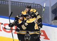 Boston Bruins centre Patrice Bergeron, centre, reacts with teammates Brad Marchand, left, and Torey Krug after scoring the game-winning goal against the Carolina Hurricanes during second overtime period on Aug. 12, 2020. The Bruins won 4-3 in Game 1.