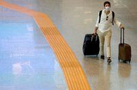 FILE PHOTO: A passenger wearing a protective face mask walks at Fiumicino Airport In Rome, Italy, May 28, 2020. REUTERS/Guglielmo Mangiapane/File Photo