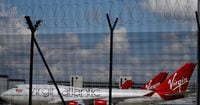 FILE PHOTO: Grounded Virgin Atlantic aircraft are seen through the fences as they remain grounded as the spread of the coronavirus disease (COVID-19) continues at Manchester Airport in Manchester, Britain June 20, 2020. Picture taken June 20, 2020. REUTERS/Phil Noble