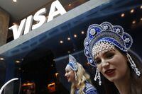 FILE - In this July 5, 2018 photo, women wearing traditional head dresses wait to greet Visa cardholders who won trips to the 2018 soccer World Cup, at the Marriott Novy Arbat Hotel, taken over by visa for the duration of the World Cup in Moscow, Russia. Mastercard and Visa are suspending their operations in Russia, the companies said Saturday, March 5, 2022, in the latest blow to the country's financial system after its invasion of Ukraine. (AP Photo/Rebecca Blackwell, File)