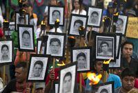 FILE - Family members of 43 missing teachers college students carry pictures of the students as they march with supporters to demand the case not be closed and that experts' recommendations about new leads be followed, in Mexico City, Tuesday, April 26, 2016. A group of international experts investigating the 2014 disappearance of 43 students in southern Mexico warned Monday, Oct. 31, 2022, that an attempt by the government to accelerate the results has created a “crisis” for the investigation and risks diminishing confidence in the outcome. (AP Photo/Rebecca Blackwell, File)