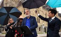 Green Party Interim Leader Amita Kuttner holds an umbrella for newly announced Deputy Leader Luc Joli-Coeur during a news conference on Parliament Hill in Ottawa, on Tuesday, June 21, 2022. THE CANADIAN PRESS/Justin Tang
