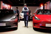 A man walks by Tesla Model 3 sedans and Tesla Model X sport utility vehicle at a new Tesla showroom in Shanghai, China May 8, 2020.